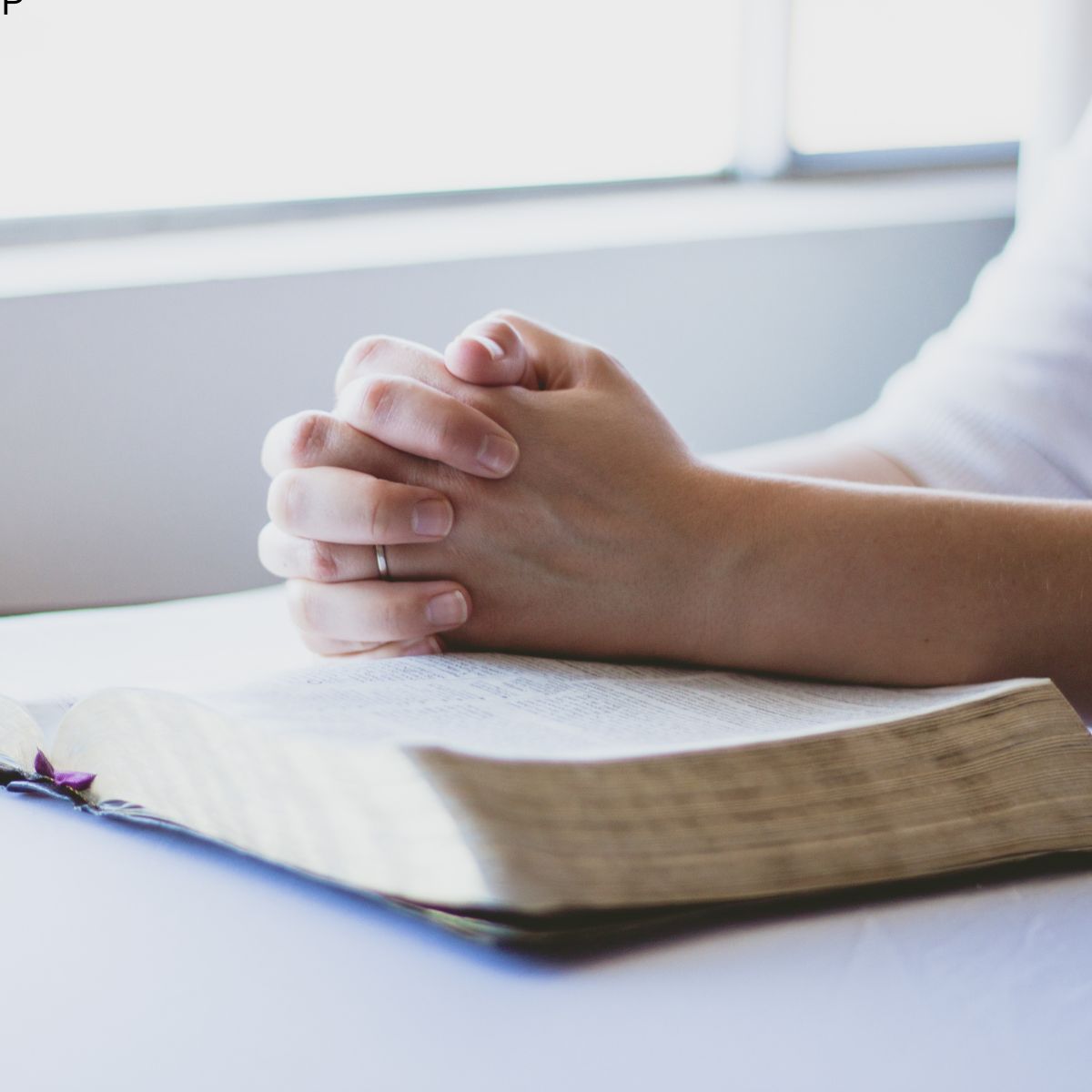 woman's hands clasped on top of BIble