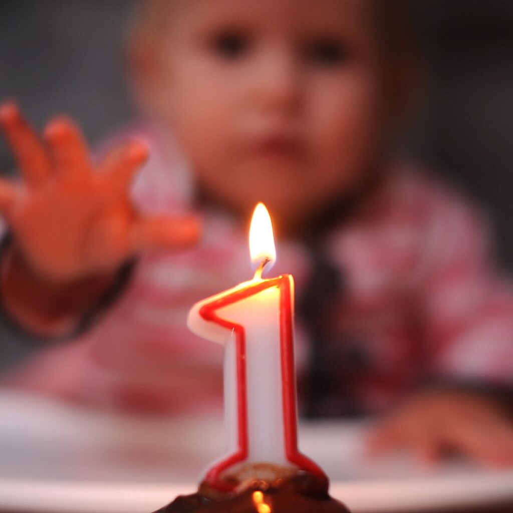 baby reaching for one year birthday candle celebrating baby's first year